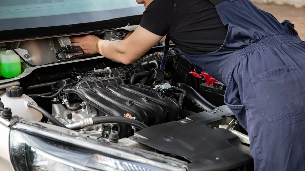 Mécanicien en bleu de travail réparant un moteur en extérieur